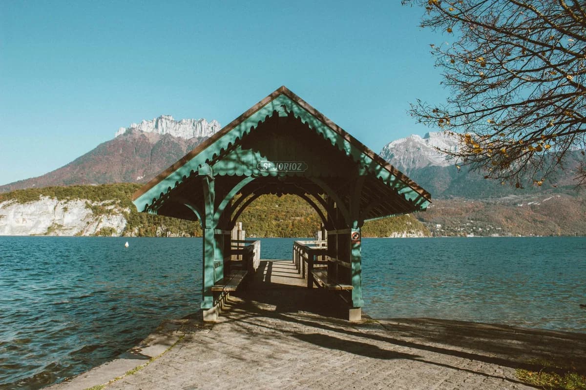 Pavillon en bois au bord d'un lac, avec des montagnes à l'arrière-plan