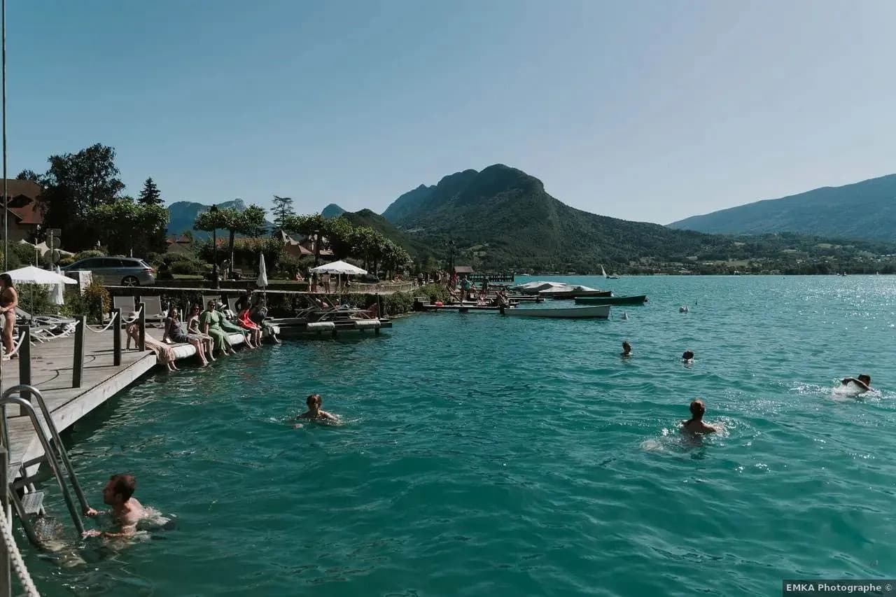 Swimmers and a wooden jetty on Lake Annecy in front of L'Abbaye de Talloires, Talloires