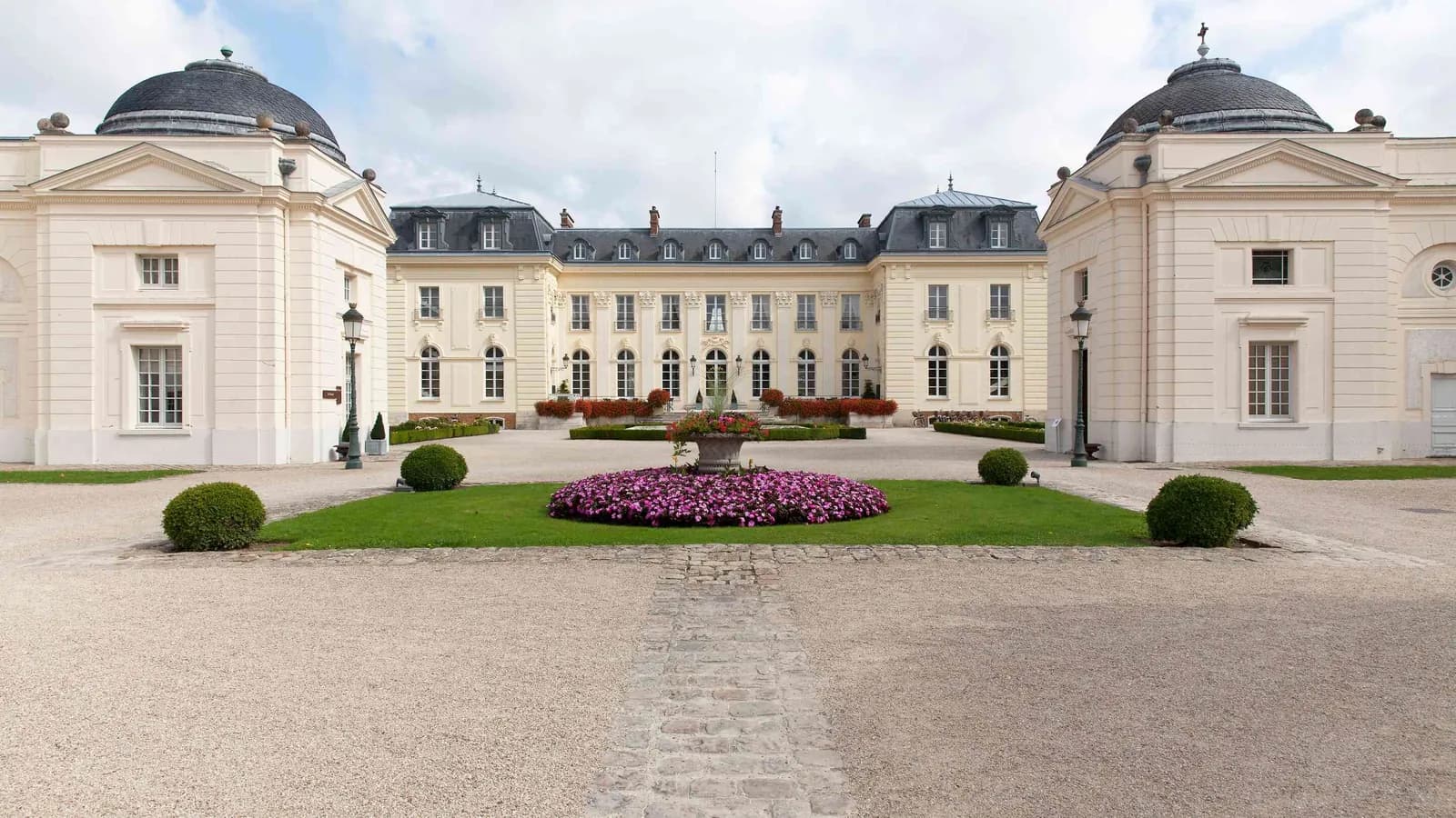 Façade du château à dômes, fontaine centrale et pelouses taillées au Domaine de la Haute Futaie, Yvelines