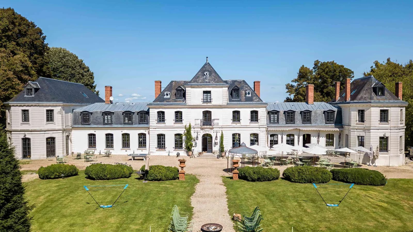 Façade de château sur une vaste pelouse, près de jardins à la française au Domaine des Hêtres Clairs, Eure