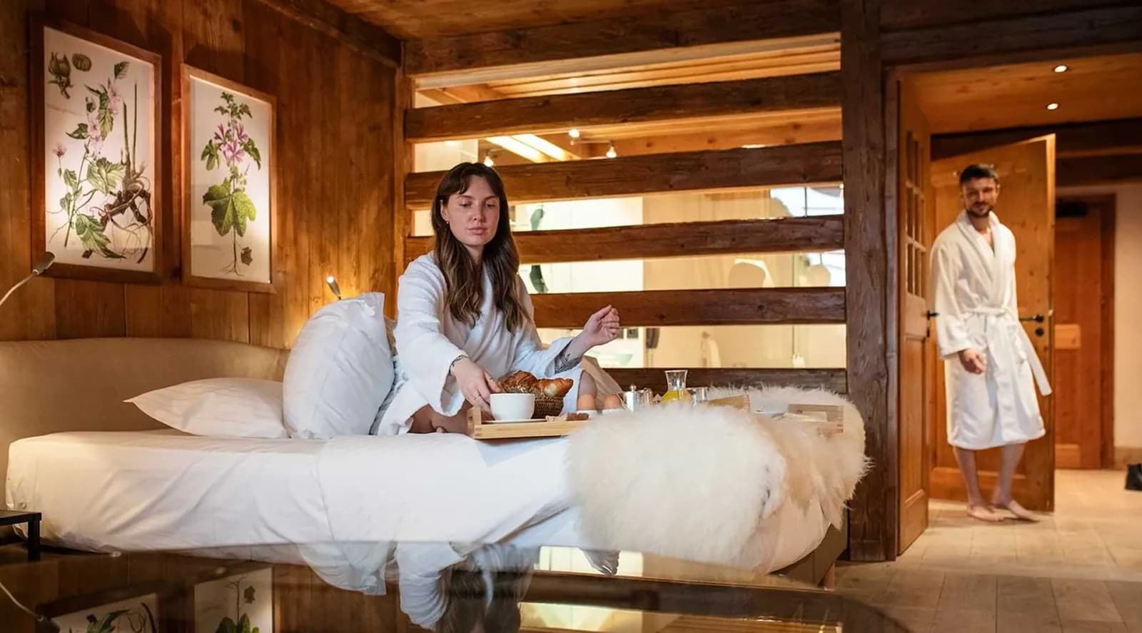 Suite with a guest reading in bed and a view to the bathroom at Hameau Albert 1er, Chamonix