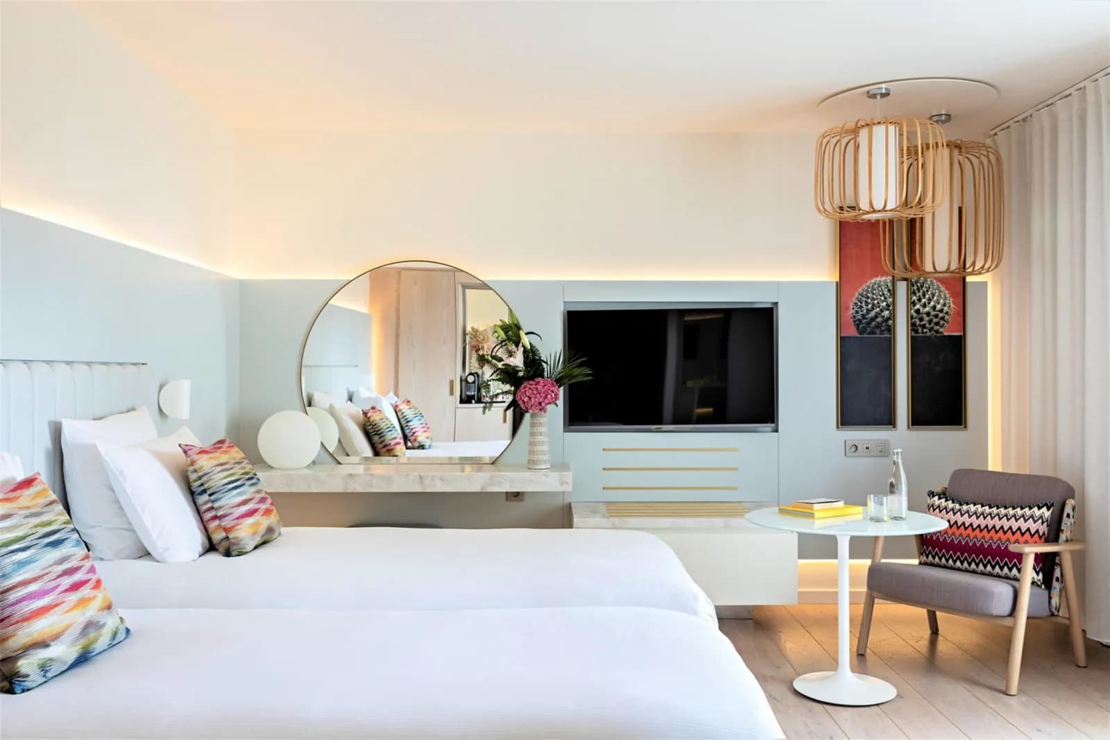 Twin room with pastel cushions, round white table and wall-mounted TV at Hôtel Croisette Beach Cannes MGallery