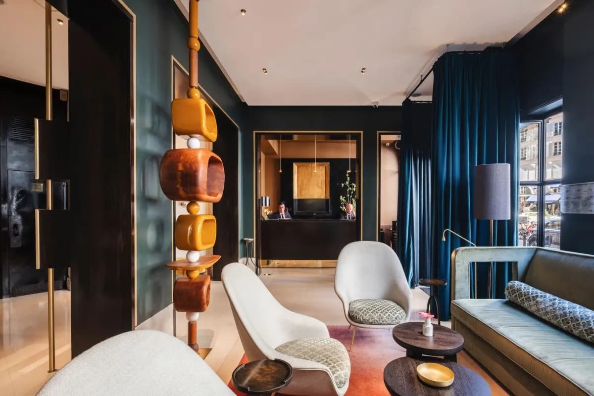 Hall de l'Hôtel Montalembert Paris avec colonne lumineuse en bois sculpté et rideaux bleu profond, dans le 7e arrondissement