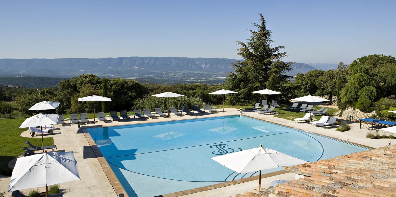 Outdoor pool with white parasols and a view over the Luberon hills at Les Bories & Spa, Gordes