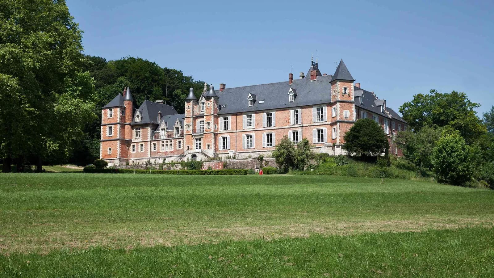 Manoir de brique et de pierre, pelouses et grands arbres au Manoir des Plaines Picardes, au nord de Paris