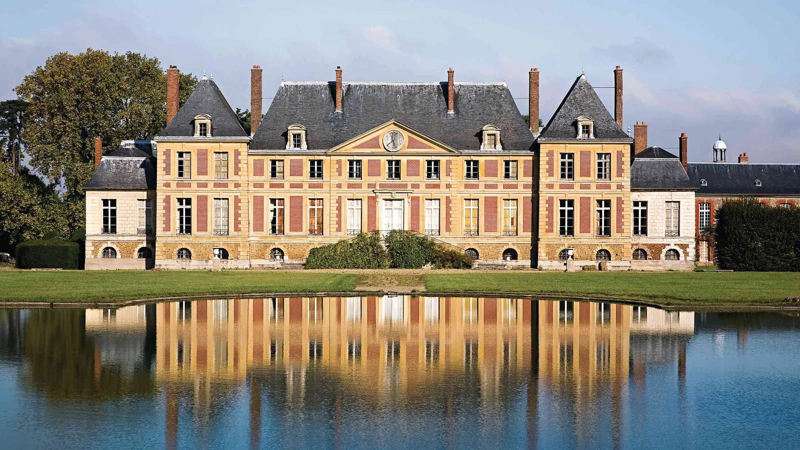 Château et bassin reflété dans le parc boisé du Manoir des Saules Dorés, en Seine-et-Marne