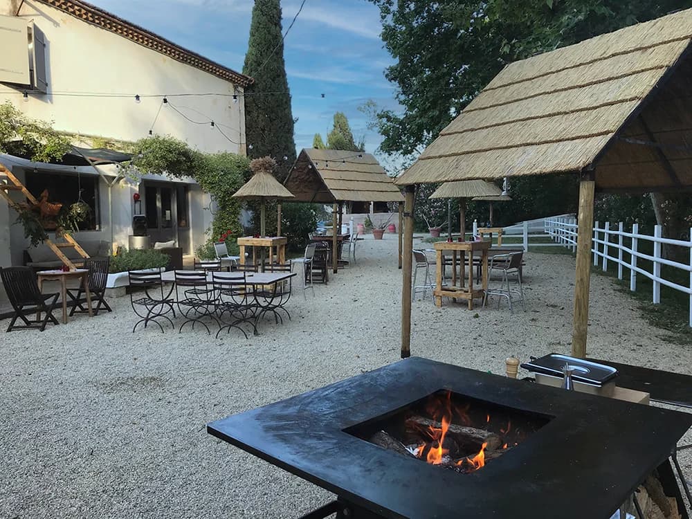 Courtyard with reed-roofed tables, a fire pit and a terrace at Mas du Ménage in Saintes-Maries-de-la-Mer