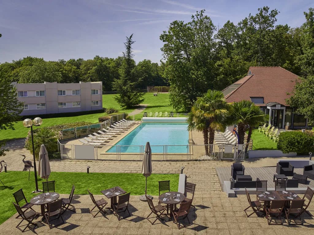 Novotel Fontainebleau Ury hotel building and terrace with pool in the wooded grounds near Fontainebleau