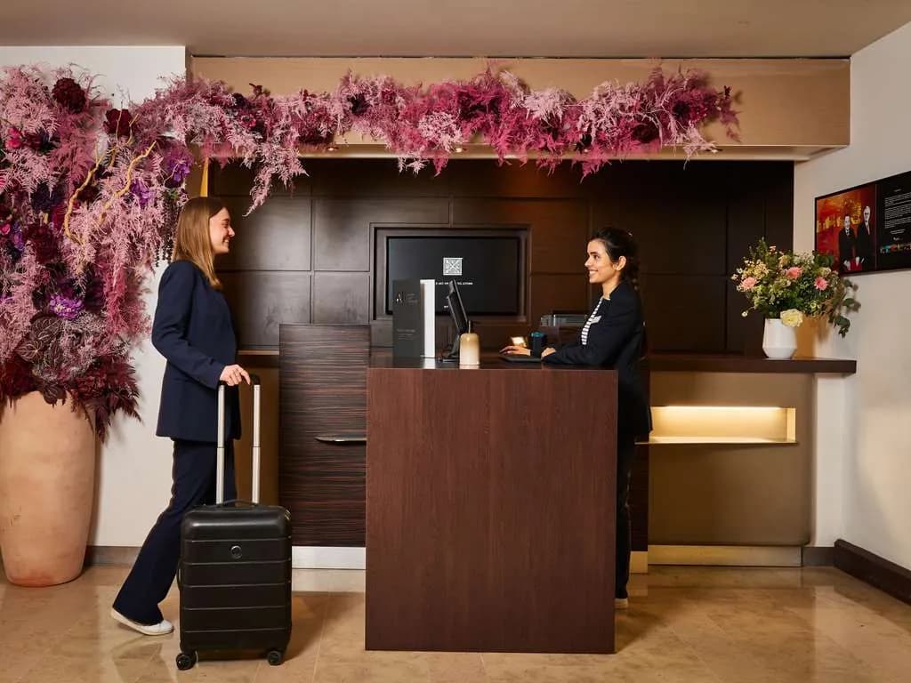 Reception desk with a floral arrangement and two staff members at Novotel Paris La Défense Esplanade