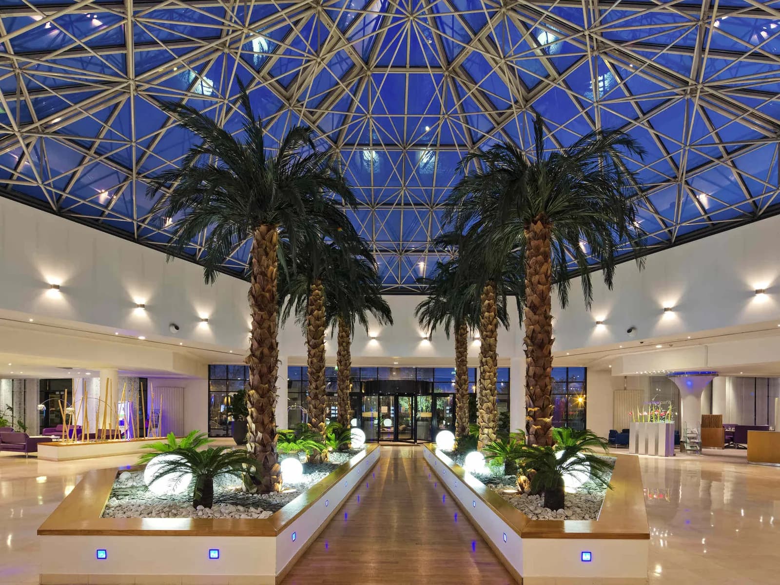 Atrium vitré du Novotel Paris Roissy CDG Convention avec palmiers et espace lounge central