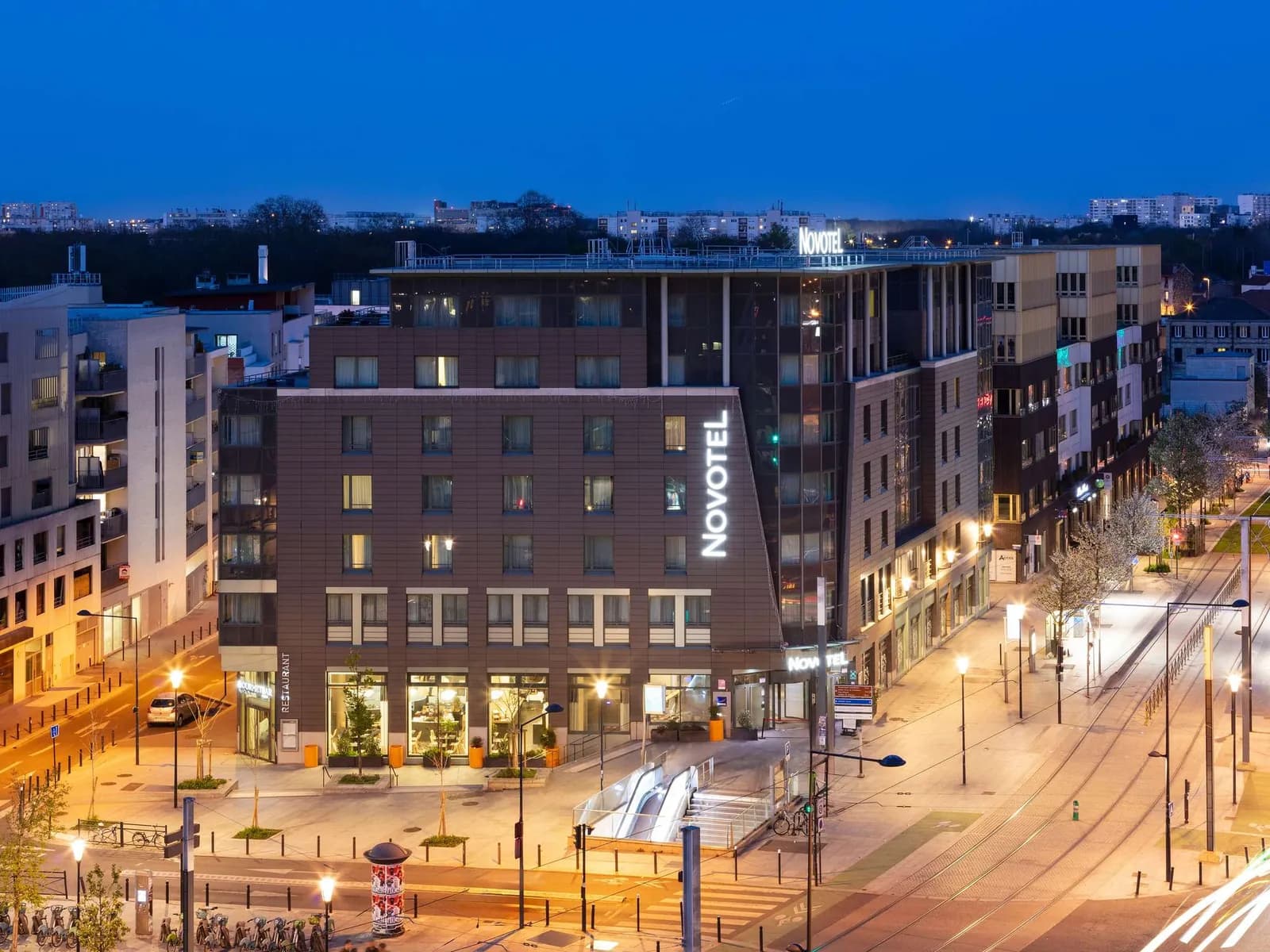 Novotel Paris Saint-Denis Stade Basilique building at dusk with its signage and city lights