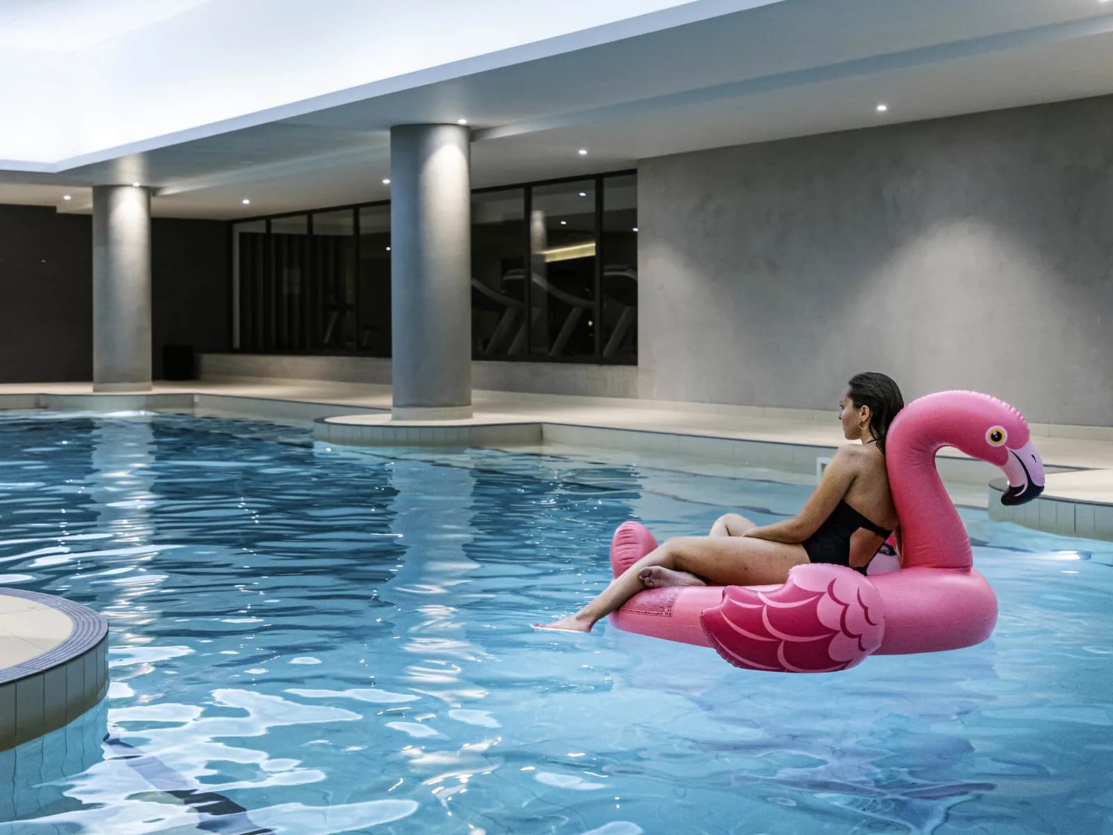 Piscine intérieure du Pullman Paris Roissy CDG Airport avec un bain de soleil flamant rose sur l'eau