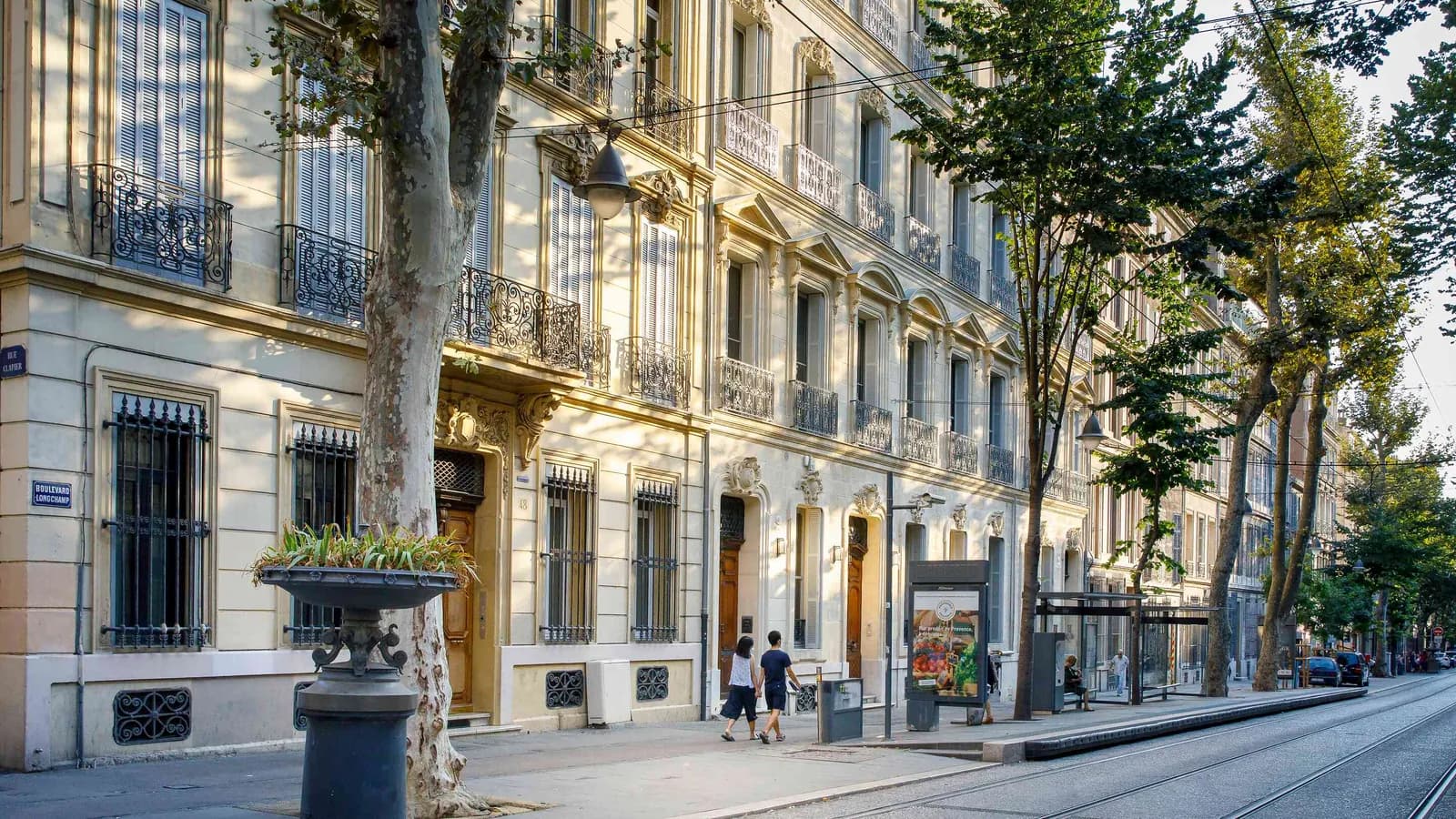 Façade en pierre et rue bordée d'arbres à Marseille, où se trouve la Villa des Verrières