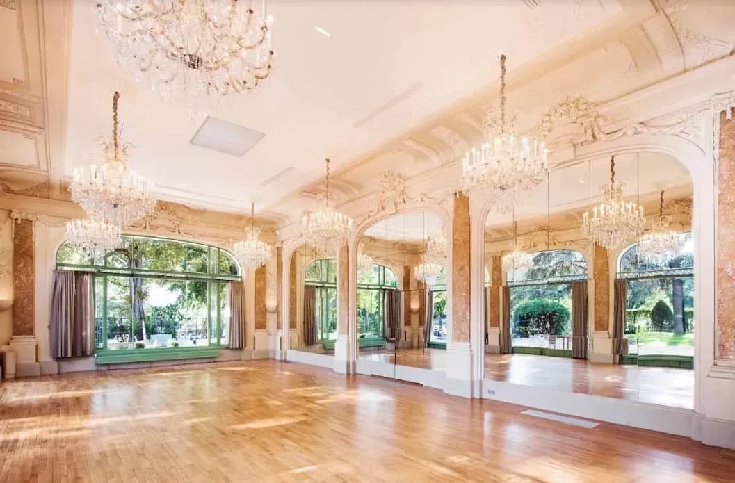 Belle Époque salon with chandeliers and tall windows onto a garden terrace