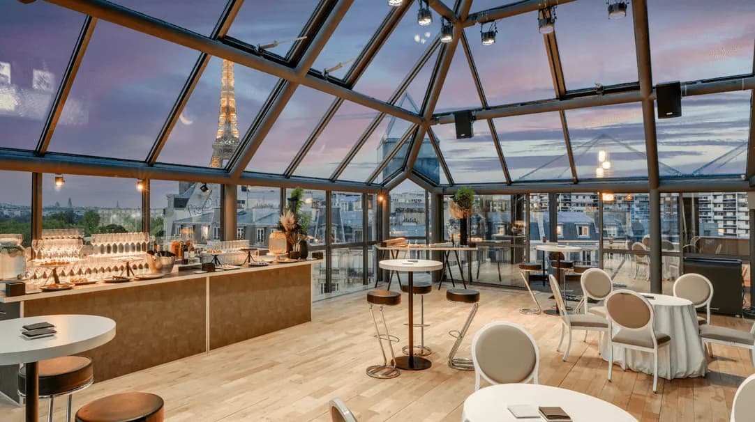 Glass-roofed atrium with bar counter, round tables and high stools