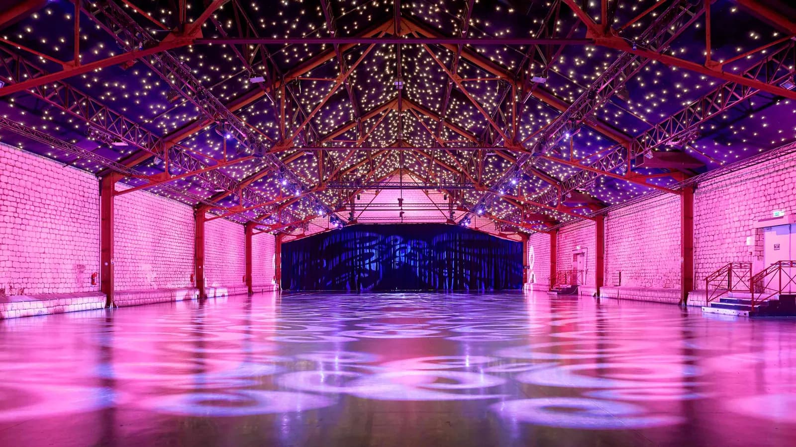Grande halle des Grandes Halles Seine, plafond étoilé, charpente apparente et lumière rose