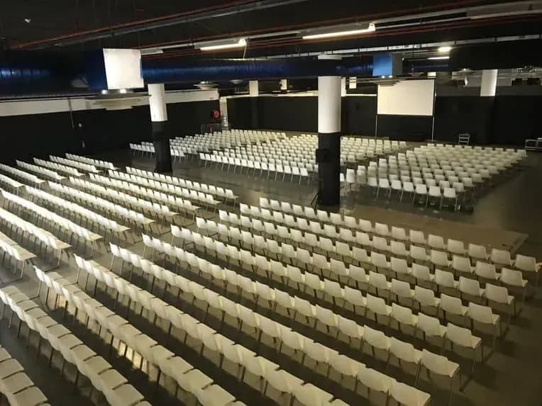 Large industrial hall with rows of chairs facing a stage