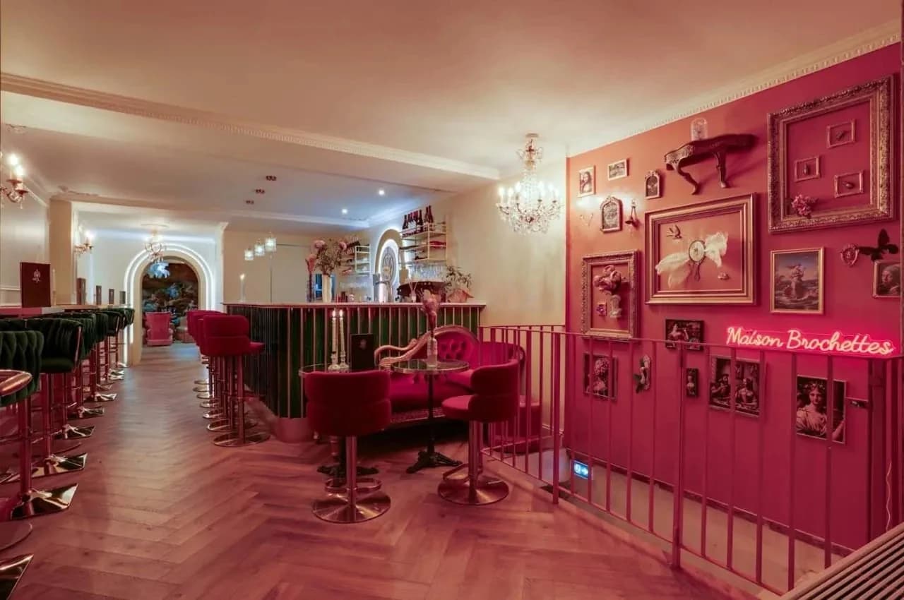 Pink-walled bar room with velvet stools and a chandelier
