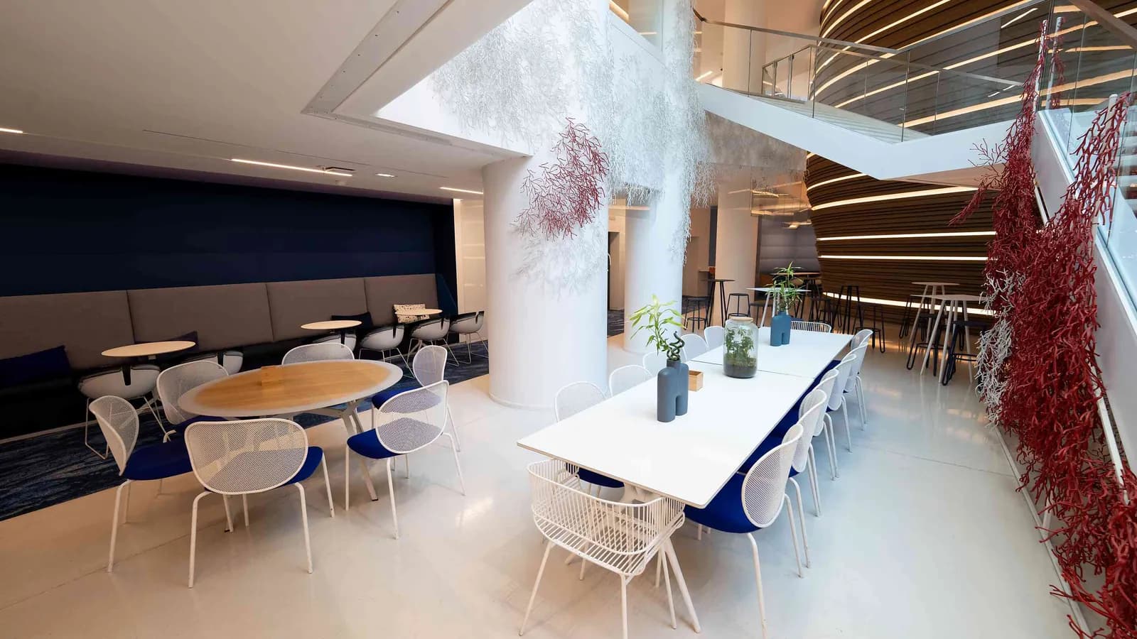 Salon du Pavillon Contemporain avec longue table blanche, chaises bleues et branches rouges