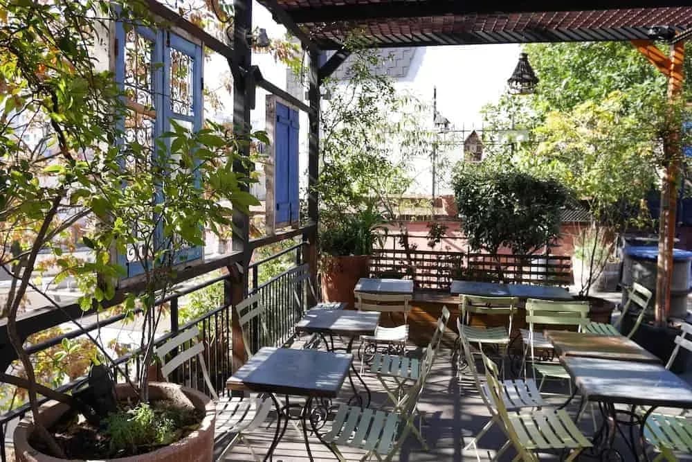 Garden terrace with blue shutters, wooden tables and a pergola roof