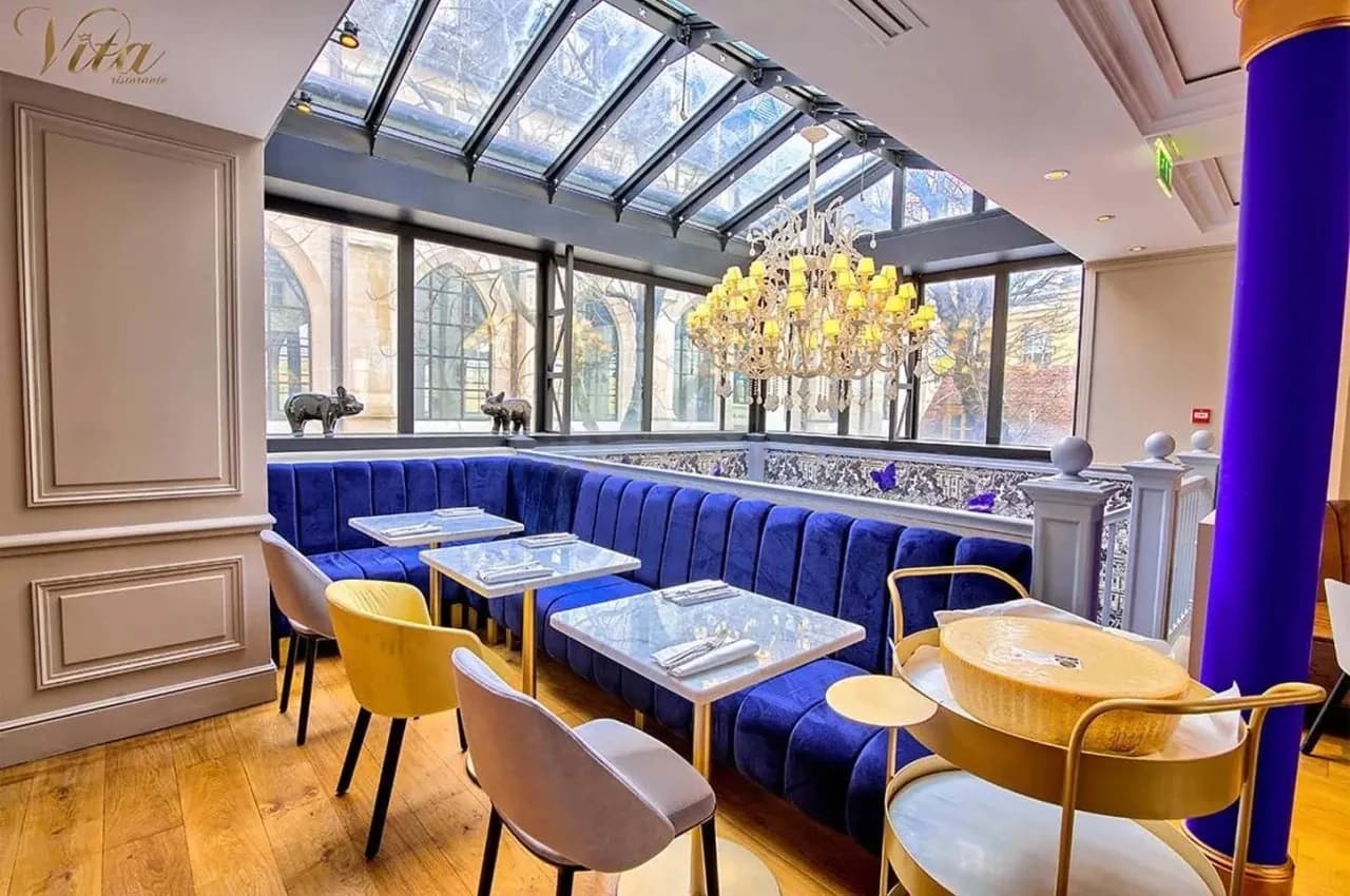 Dining area with a glass roof, blue velvet banquettes and a crystal chandelier.