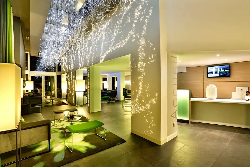 Lobby of Best Western Plus Hôtel du Parc Chantilly with a light-tree installation, green accents and a reception desk