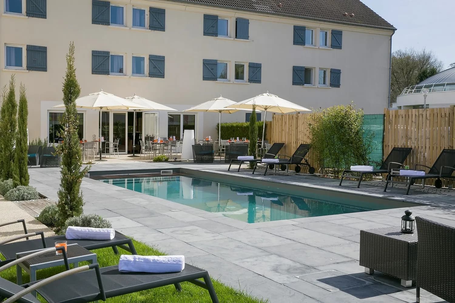 Outdoor heated swimming pool and terrace with parasols at Best Western The Wish Versailles, Guyancourt
