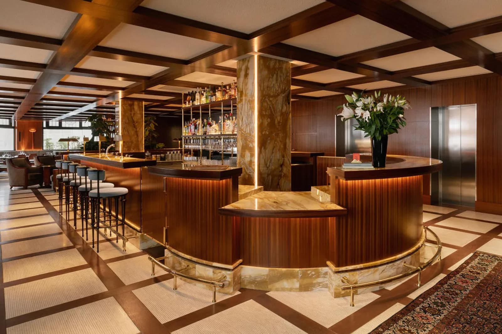 Bar and lounge of Hôtel des Grands Voyageurs in Paris, with wood panelling, a marble column and a curved bar