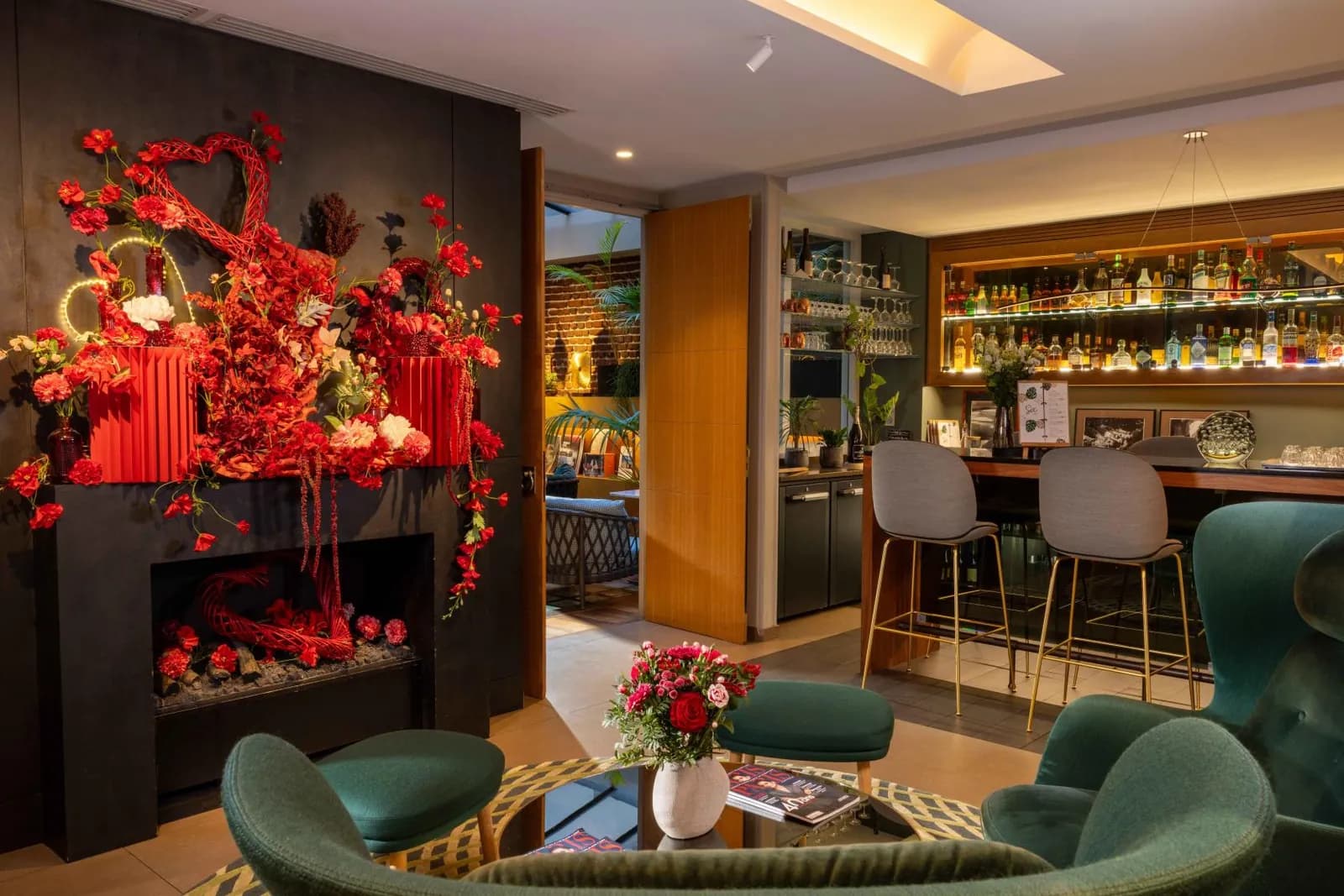 Lounge bar at Hôtel Le Six Paris with green velvet armchairs, a fireplace and a glass-topped table in the 6th