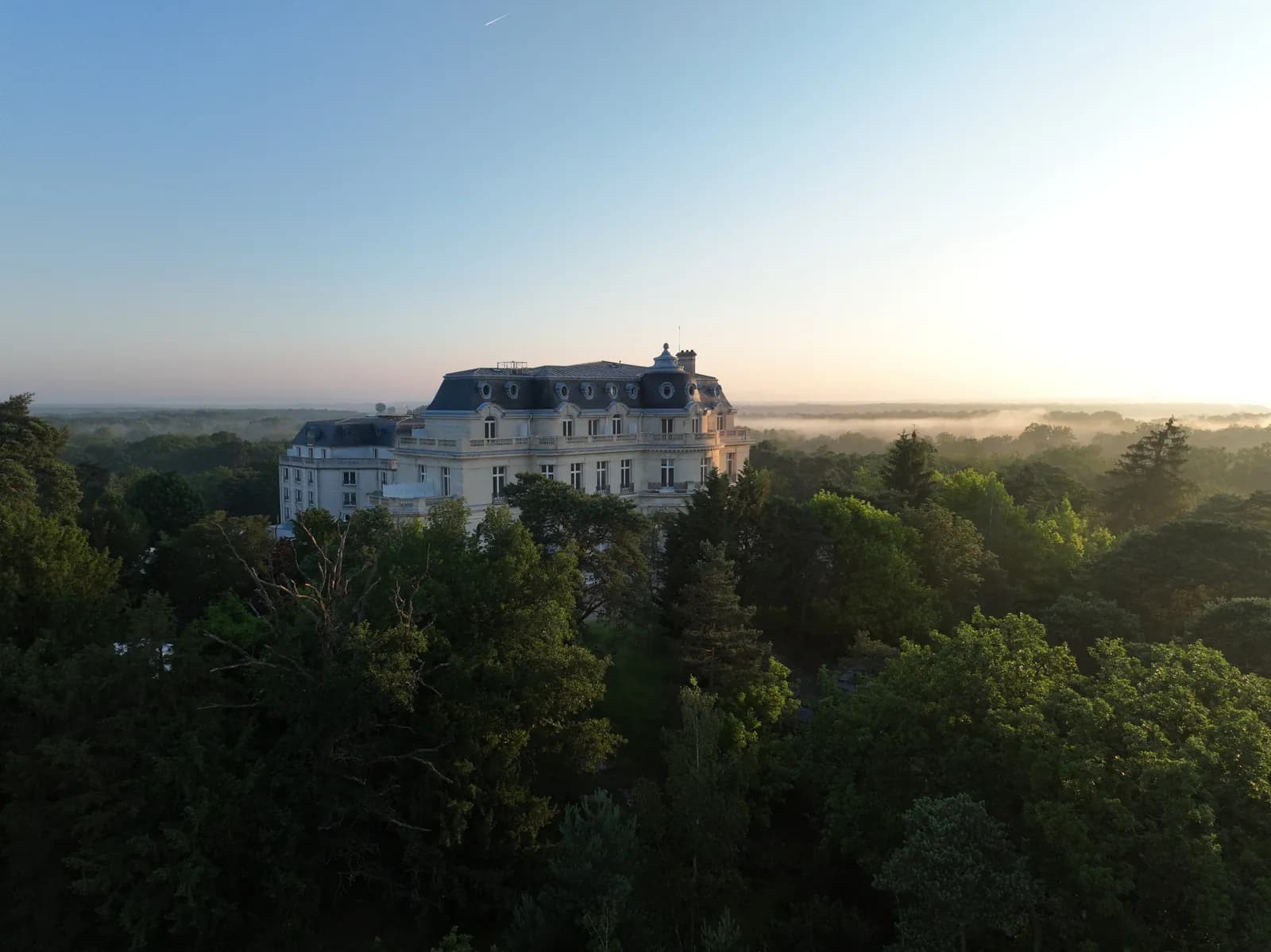Château Mont Royal at dawn above the treetops, InterContinental Chantilly hotel near Paris