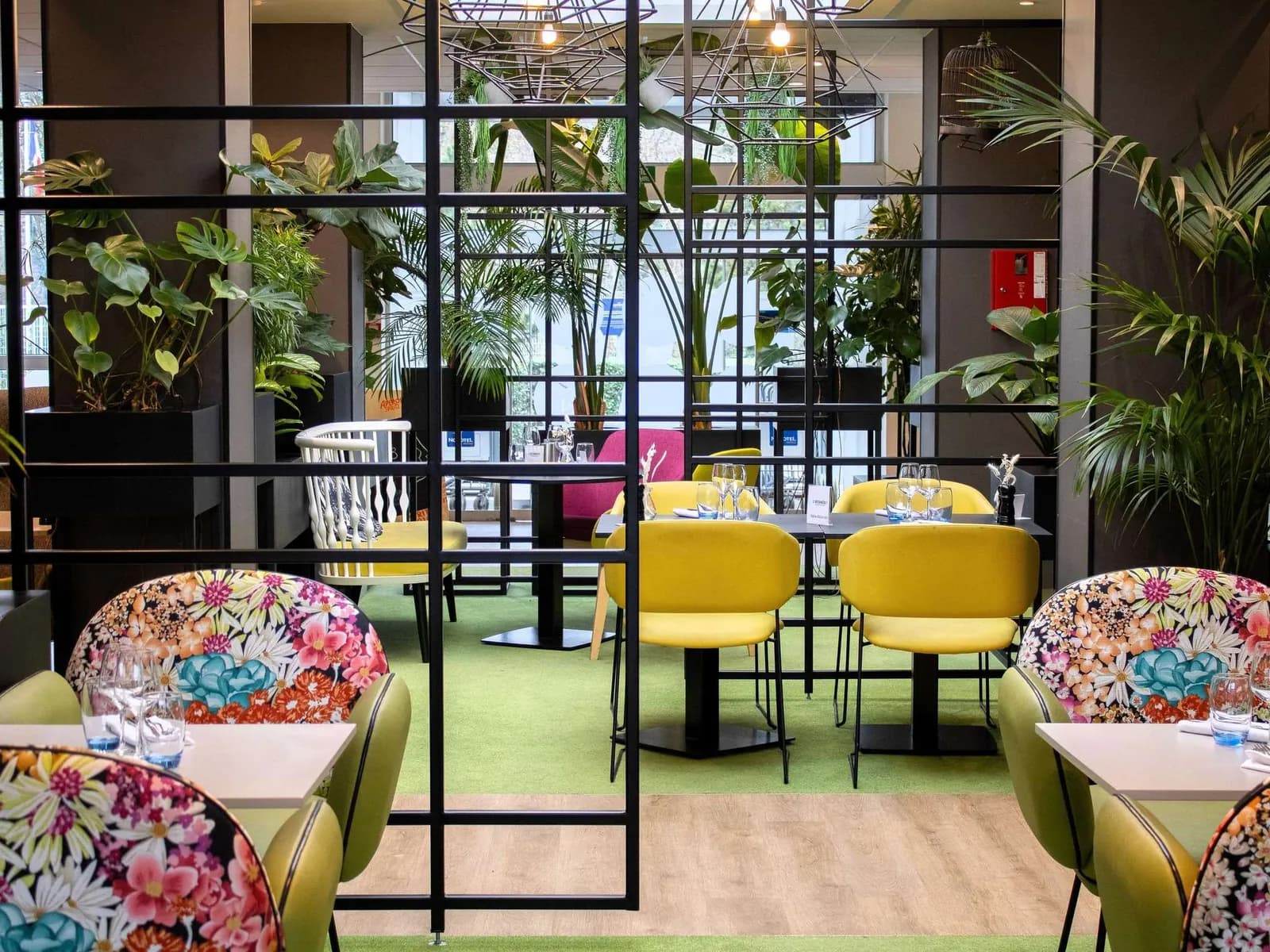 Colourful lounge with yellow armchairs and green plants at Novotel Évry-Courcouronnes, Évry