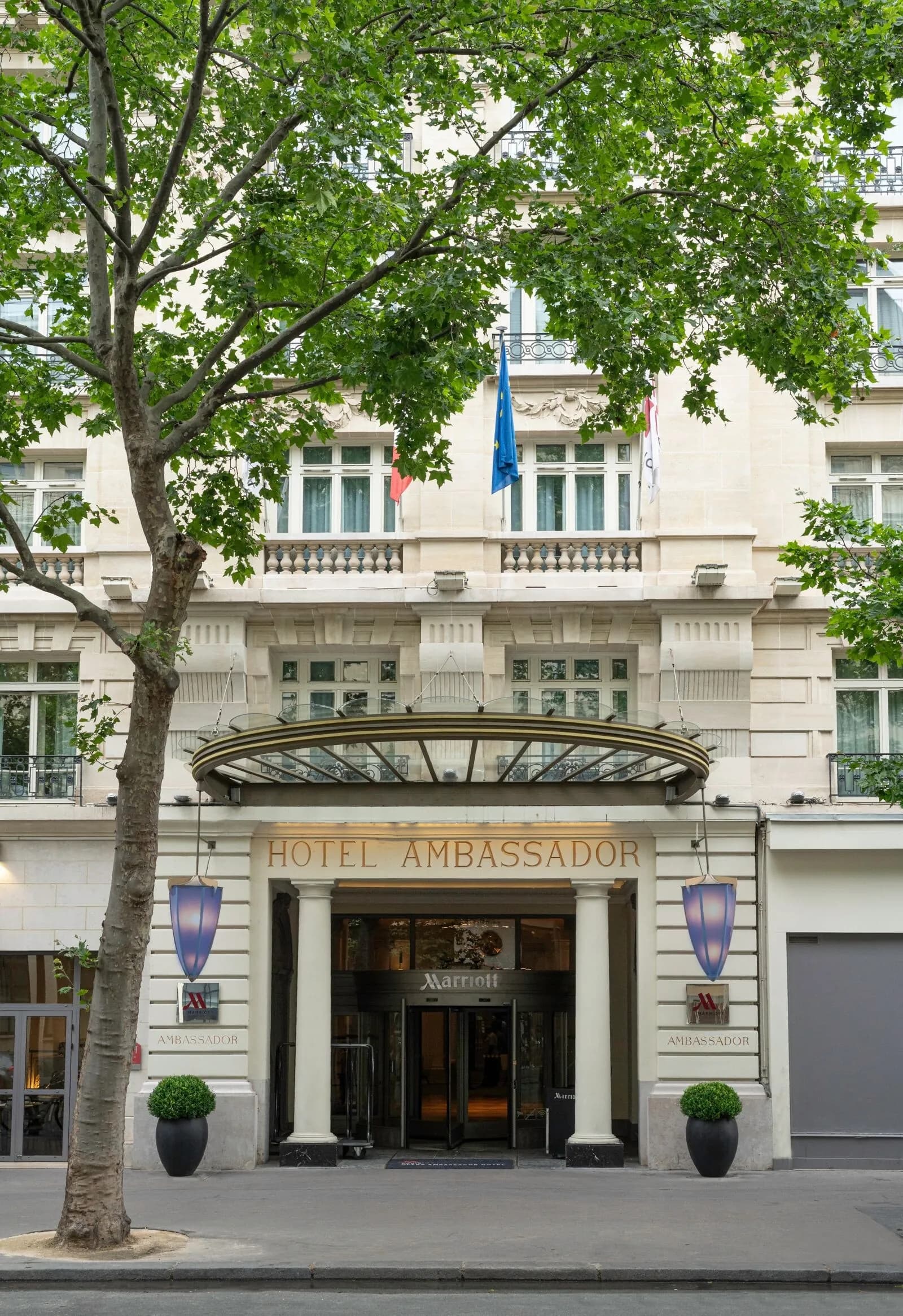 Exterior of the Paris Marriott Opera Ambassador Hotel on boulevard Haussmann, with its classic stone facade and entrance