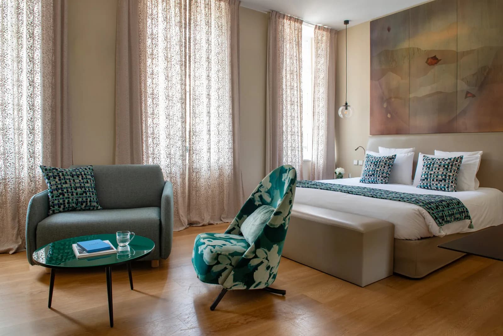 Suite-style guest room with a green armchair and a bed with teal throws at Régent Petite France, Strasbourg