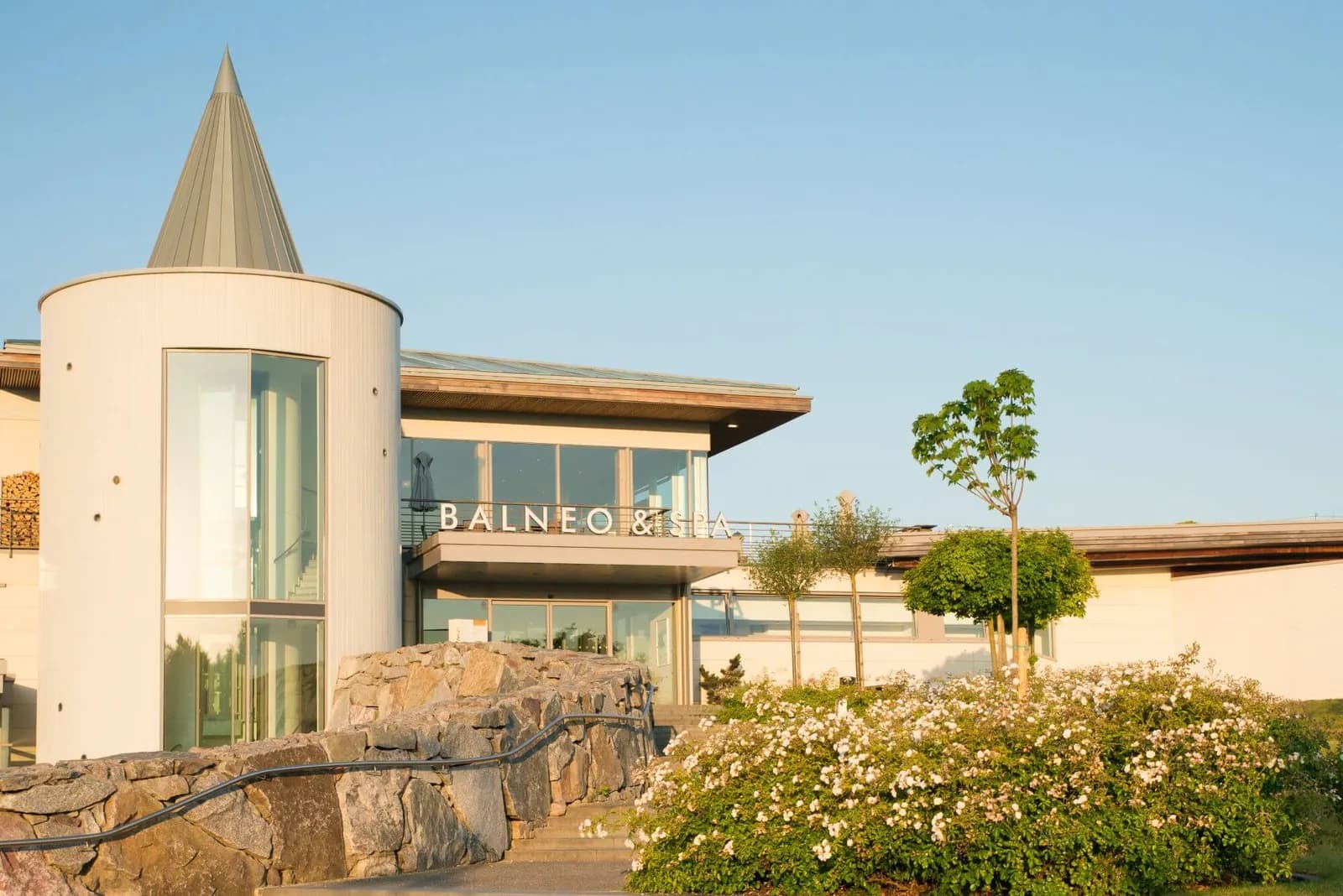Exterior of the Balneo and Spa building of Resort Barrière Ribeauvillé with a bright flower bed in the Alsace