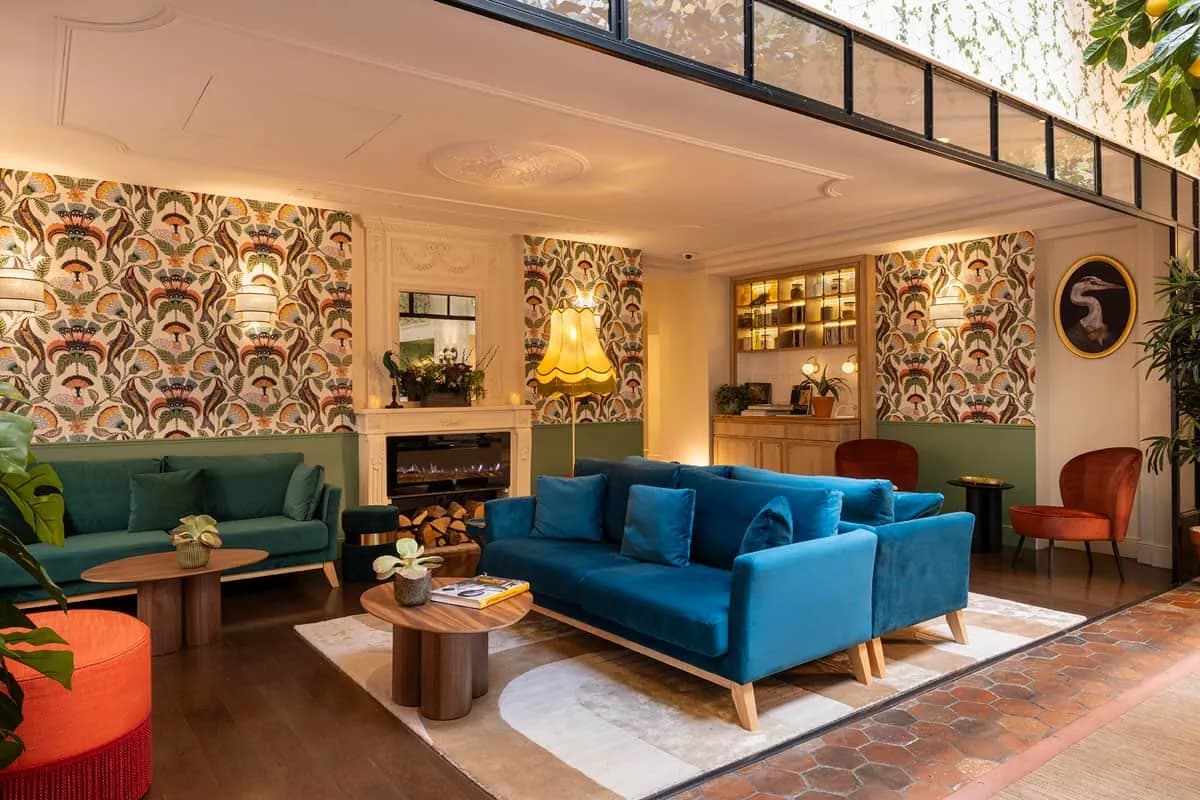 Lounge of Hôtel & Spa Royal Madeleine in Paris with patterned wallpaper, blue sofas and a glass roof