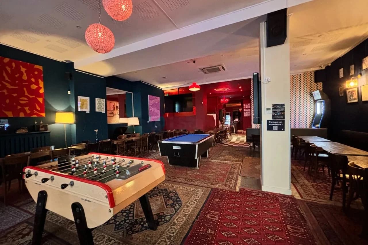 Room with a foosball table and a red patterned carpet