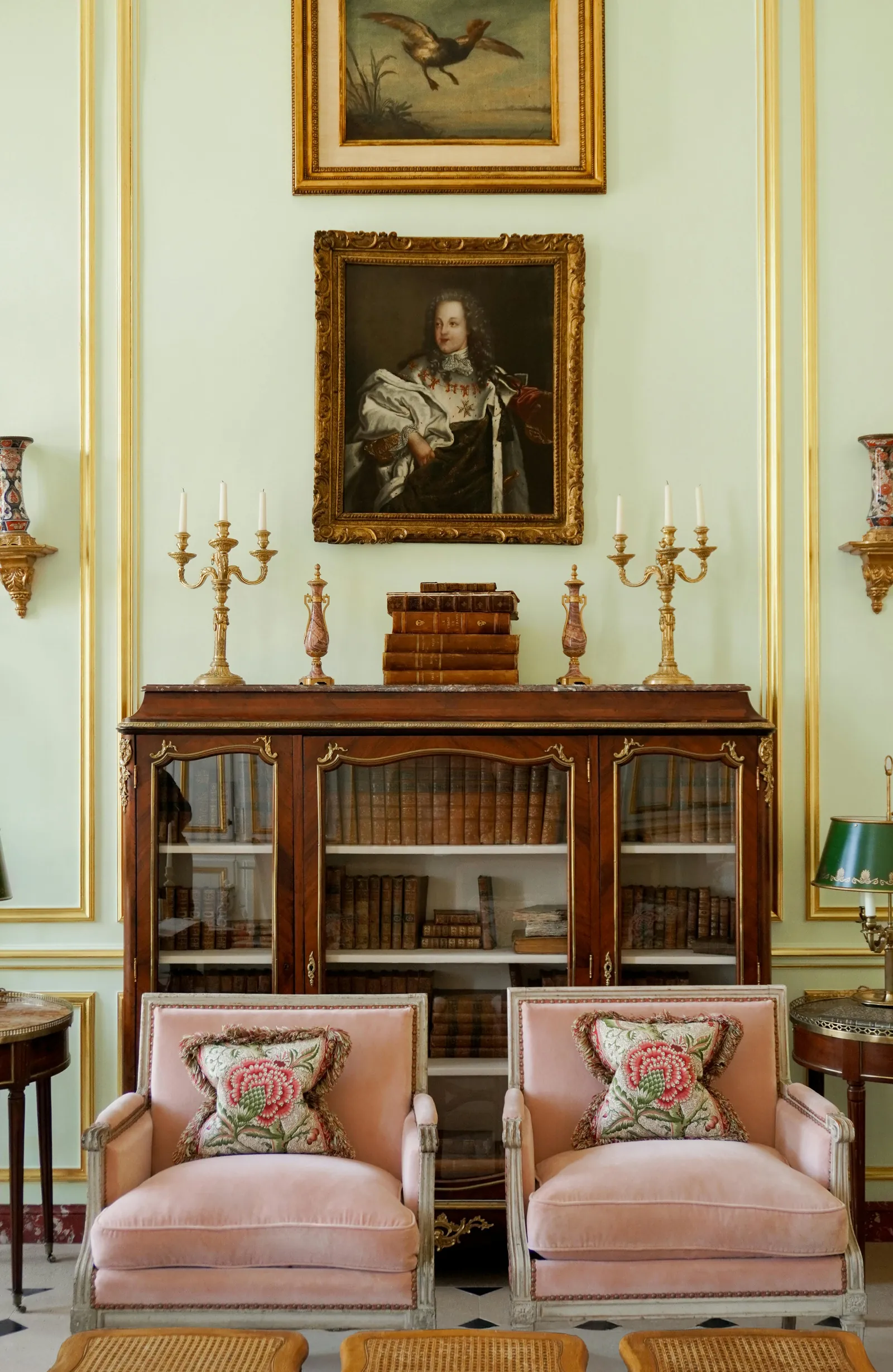 Lounge with pink armchairs, antique cabinet and framed oil painting at Airelles Château de Versailles