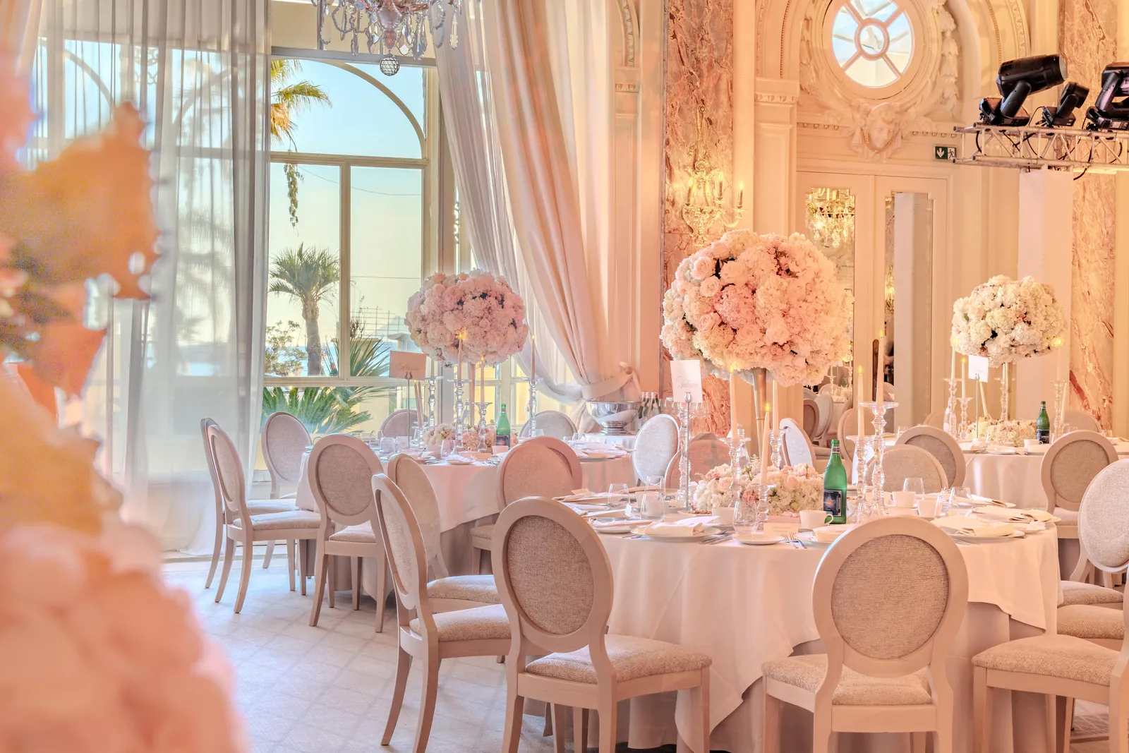 Grand salon décoré de compositions florales roses pour un dîner de mariage au Carlton Cannes