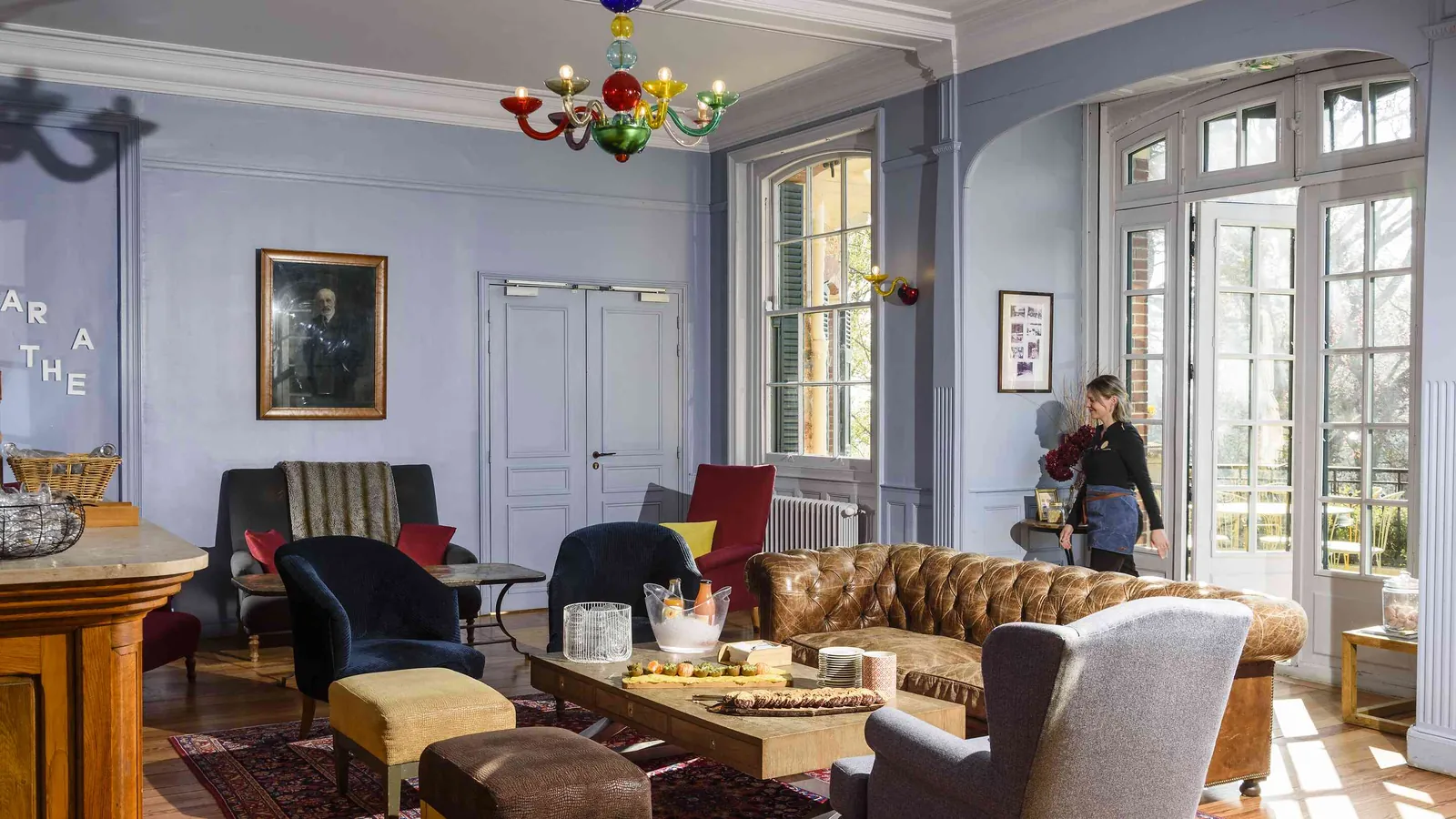 Salon avec lustre, portrait et canapé profond au Château des Berges Sereines, dans les Yvelines