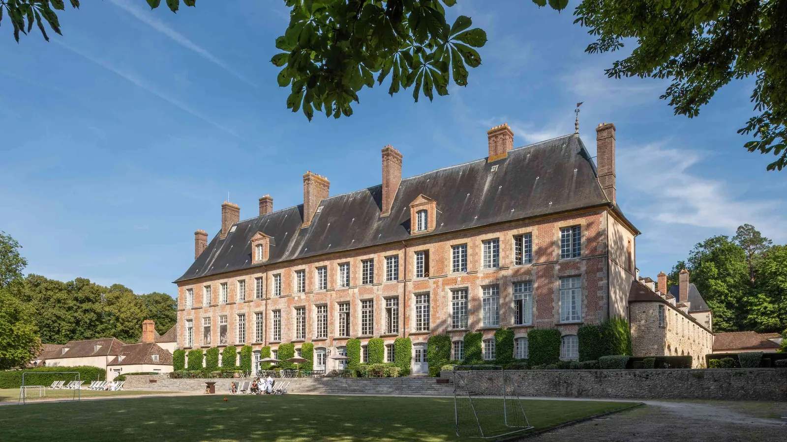 Façade de château classique, pelouse et marronnier au Château des Grandes Perspectives, à l'ouest de Paris