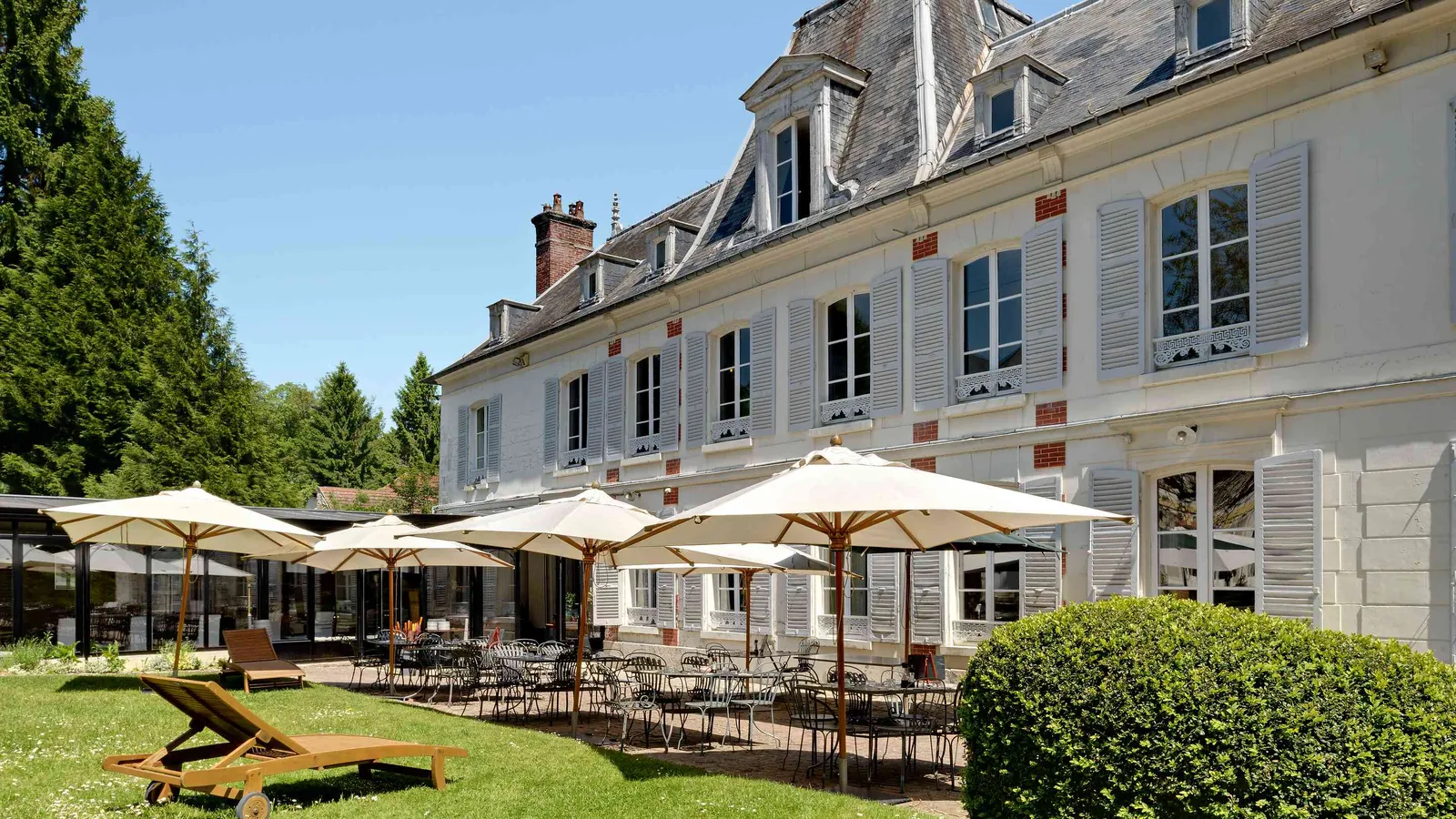 Terrace with parasols and loungers beside the château at Château des Lauriers Champêtres, Eure, Normandy