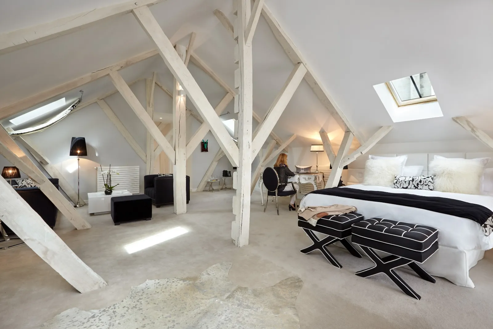 Attic suite with white timber beams, skylights and a king bed at Clarance Hôtel, Lille