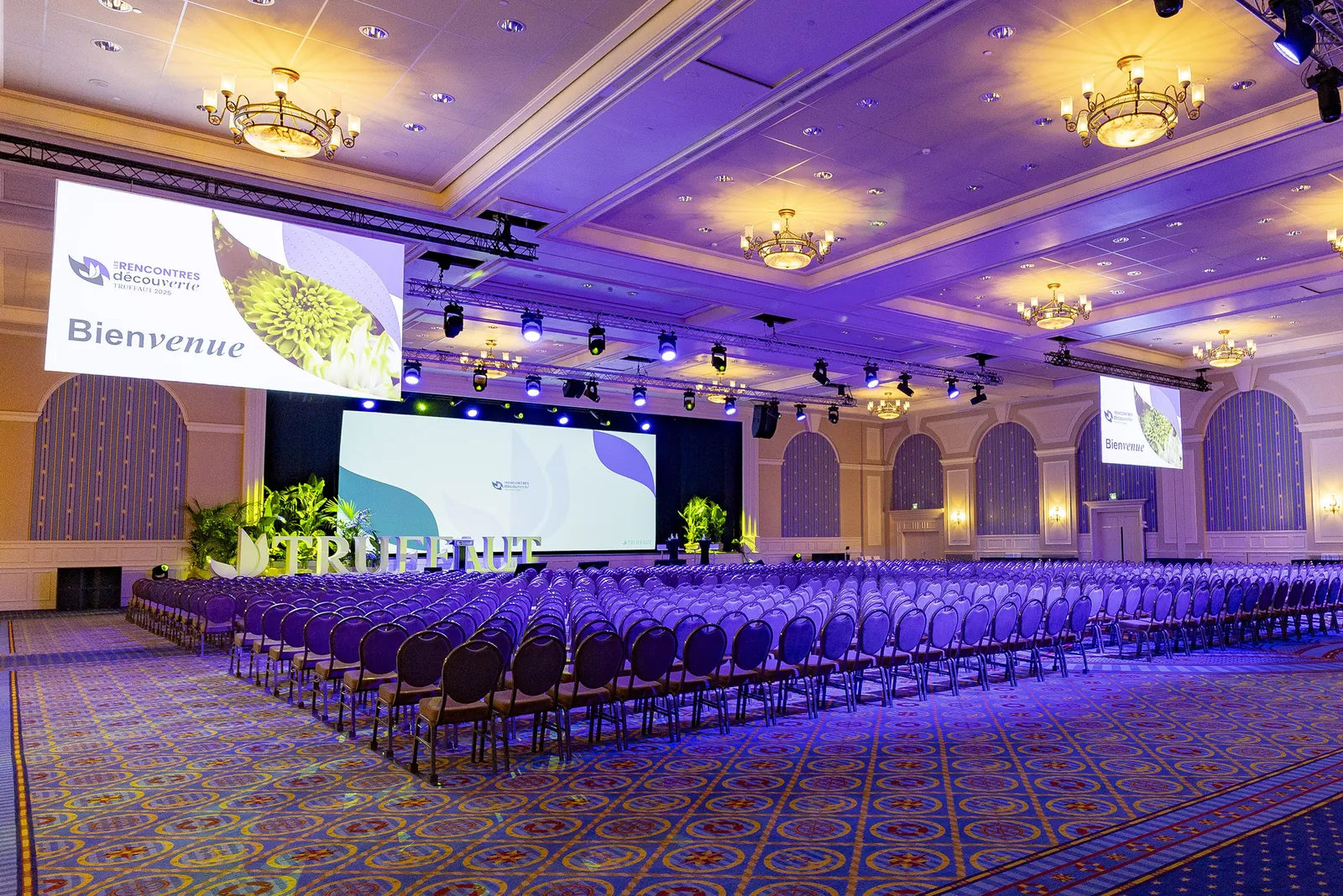 Conference ballroom with rows of chairs, chandeliers and a welcome screen at Disney's Newport Bay Club