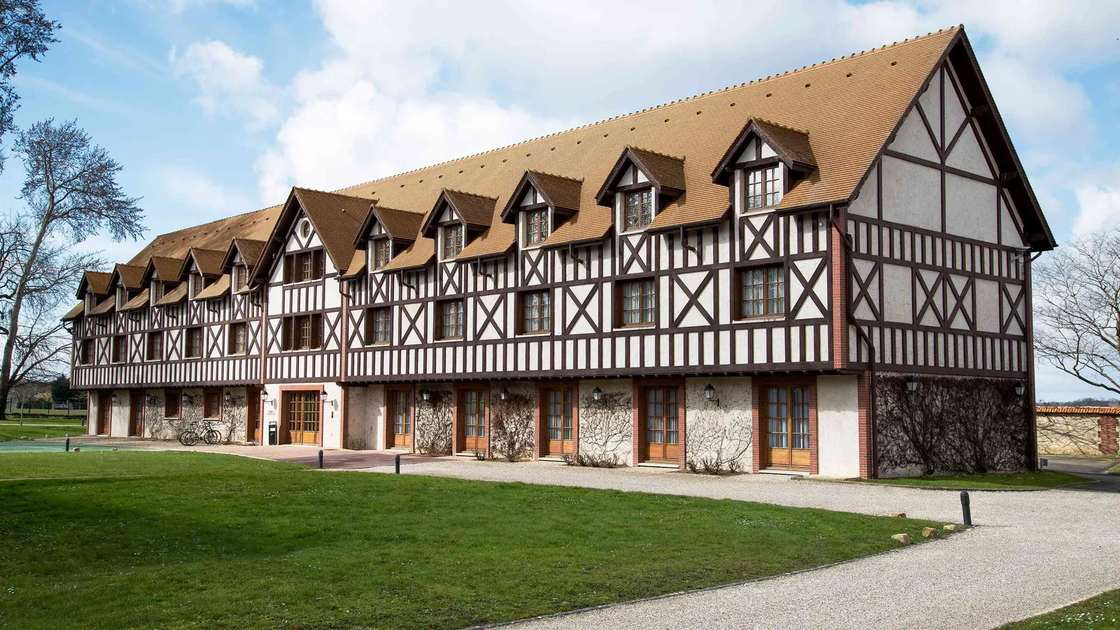 Long bâtiment à colombages, lucarnes et pelouses au Domaine de la Haute Futaie, dans les Yvelines