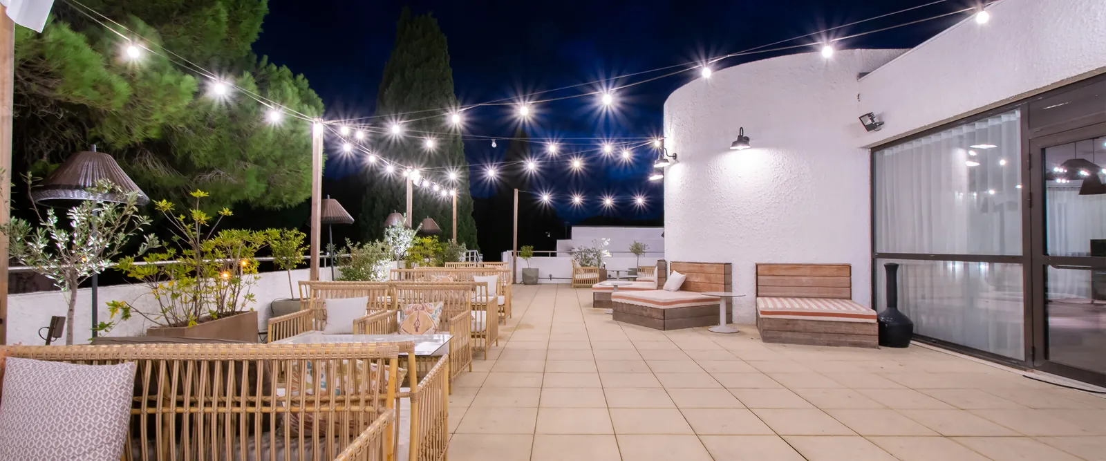 Terrasse du soir éclairée de guirlandes et de mobilier en bois au Domaine des Pinèdes Languedociennes, Hérault