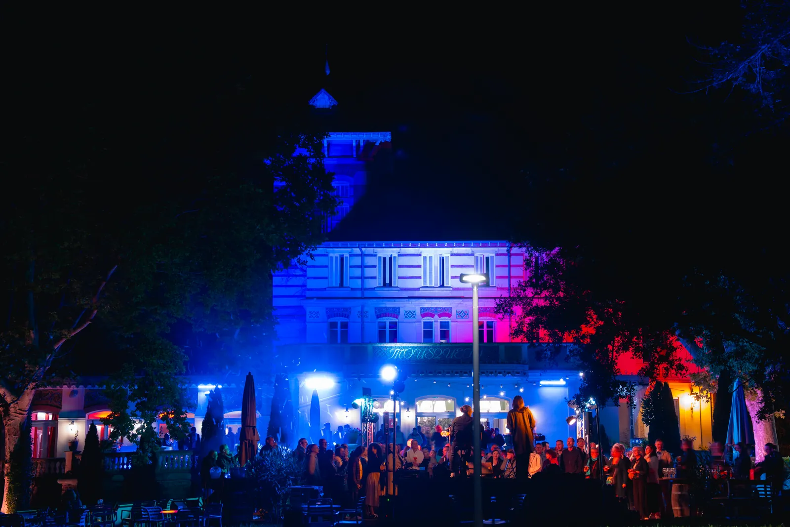 Evening event with coloured stage lighting in front of the main building at Domaine des Platanes du Vaucluse
