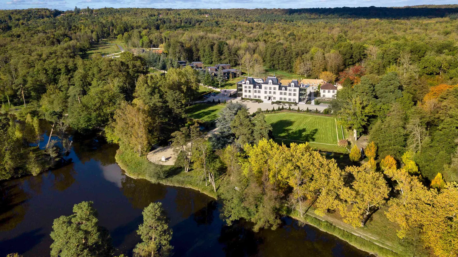 Aerial view of Domaine des Sources Vertes with its river and wooded estate in the Yvelines