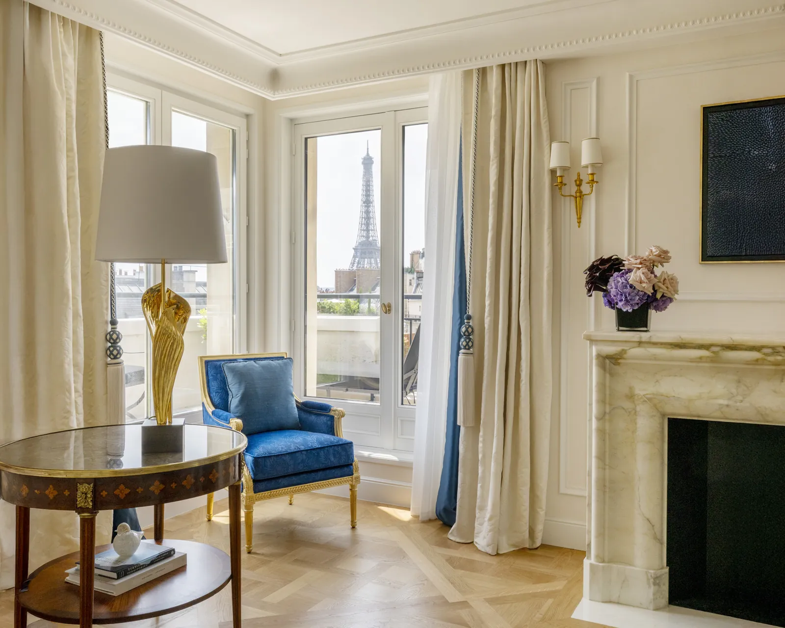 Salon de suite avec fauteuil bleu et vue sur la tour Eiffel au Four Seasons Hotel George V, Paris