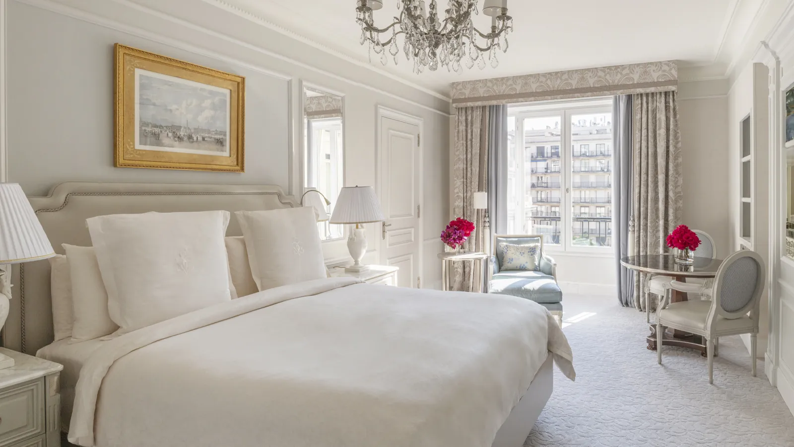 Chambre avec linge blanc, tableau doré et grandes portes-fenêtres au Four Seasons Hotel George V, Paris