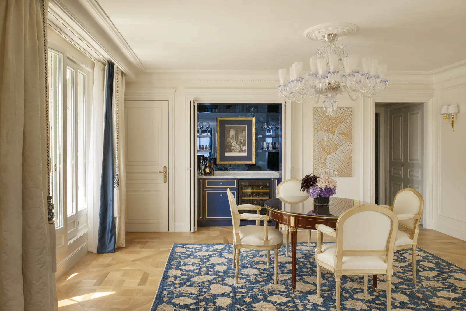Coin repas avec table en noyer, chaises crème et tapis bleu à motifs floraux au Four Seasons Hotel George V, Paris